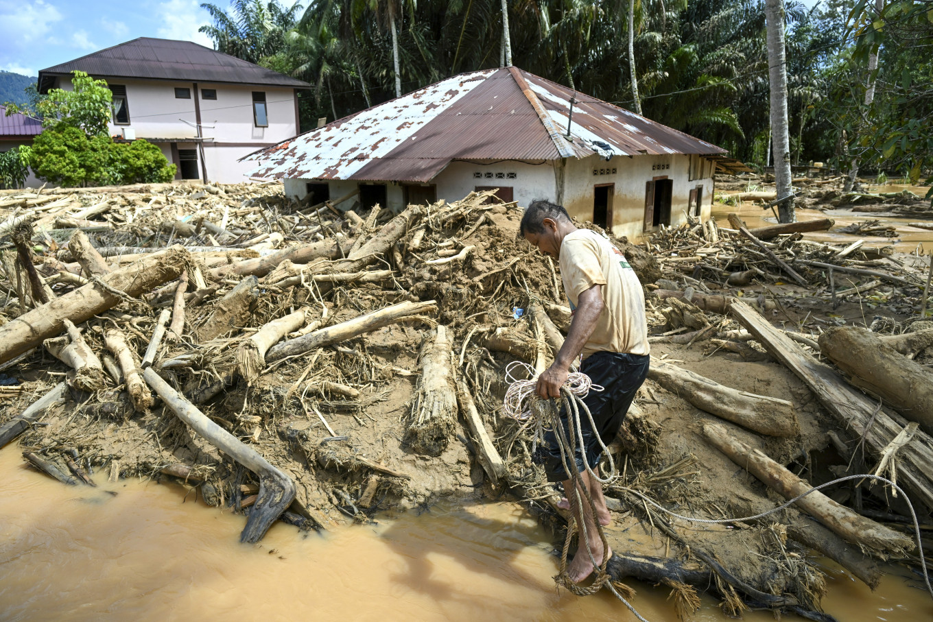 A villager affected by flash floods walks amongst a pile of log debris on Dec. 2, 2025, in Tukka village, Central Tapanuli regency, North Sumatra. (Photo AFP/YT Hariono)
